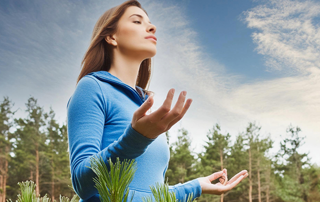 Femme méditant dans la forêt, respiration profonde