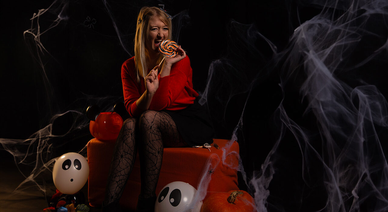 Nass Halloween Une femme relaxée sur un canapé, en train de manger un bombom aux couleurs d'Halloween.