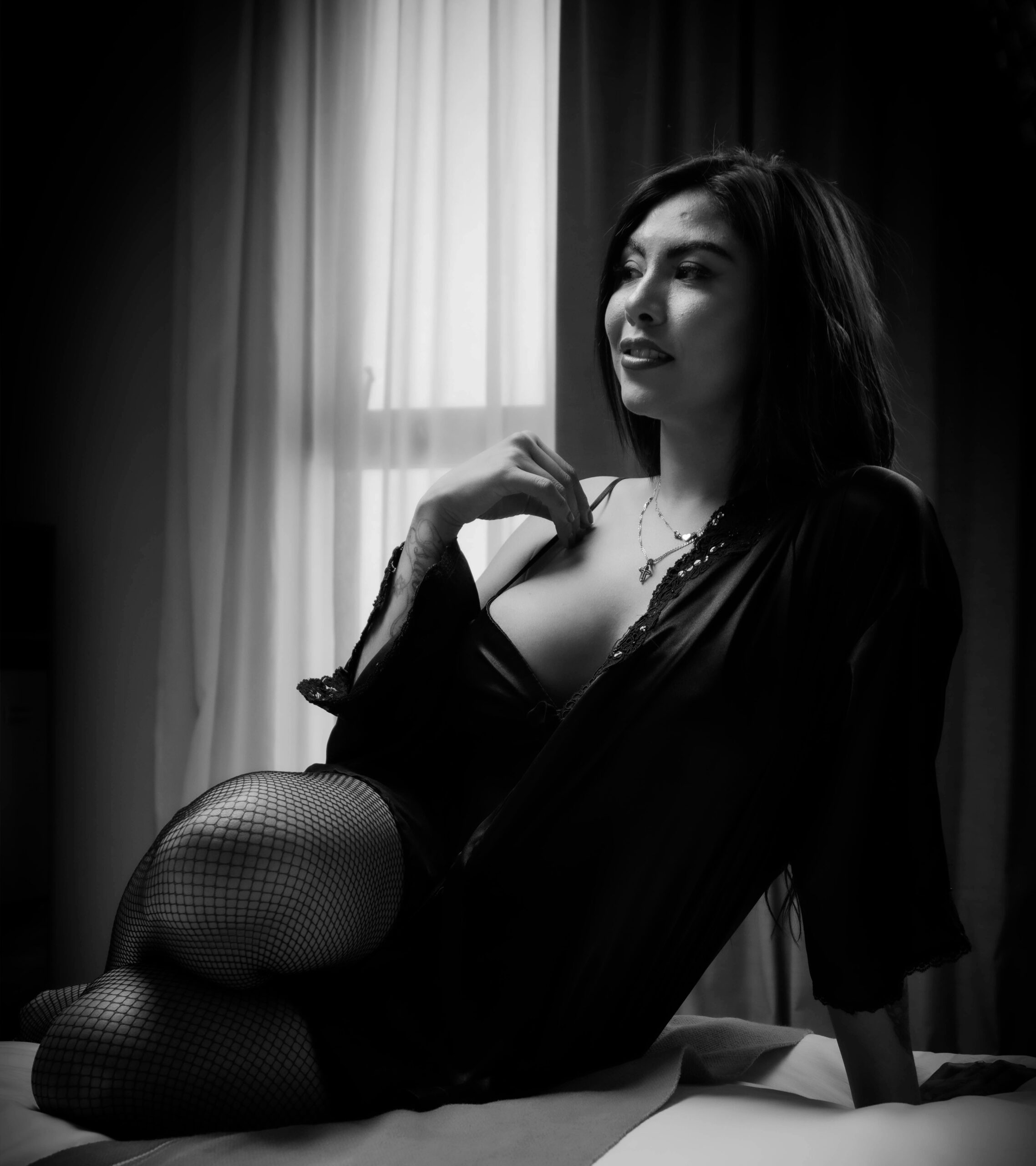 Une femme assise sur un lit, capturant l'élégance d'une séance photo boudoir